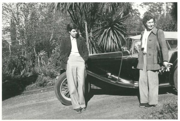 June Barnett Black and white photograph of two women standing against vintage car.