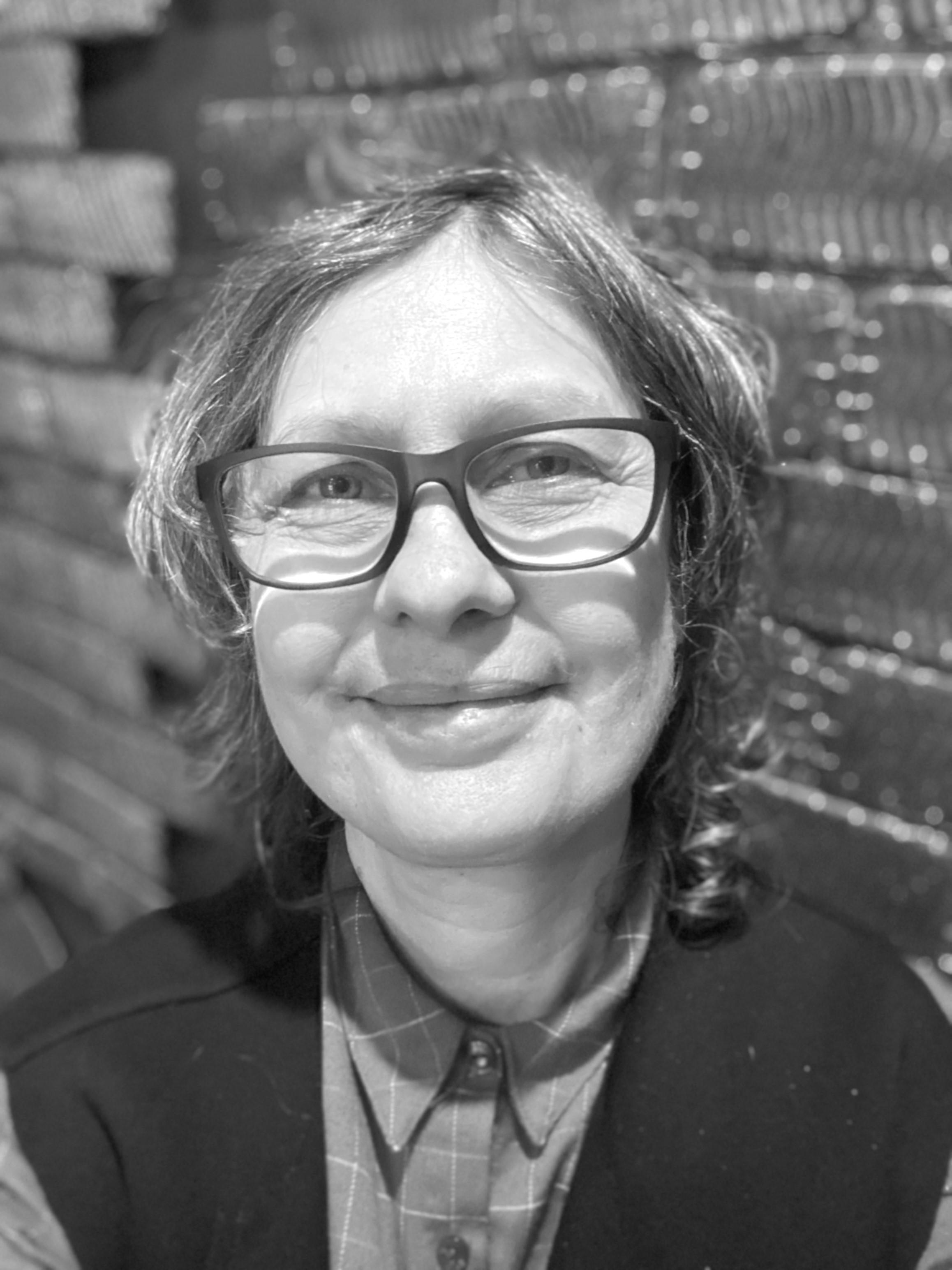 Black and white photograph of a woman against a brick wall.