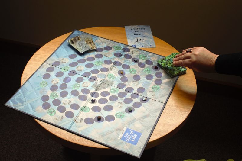 Person playing a board game on low wooden table.