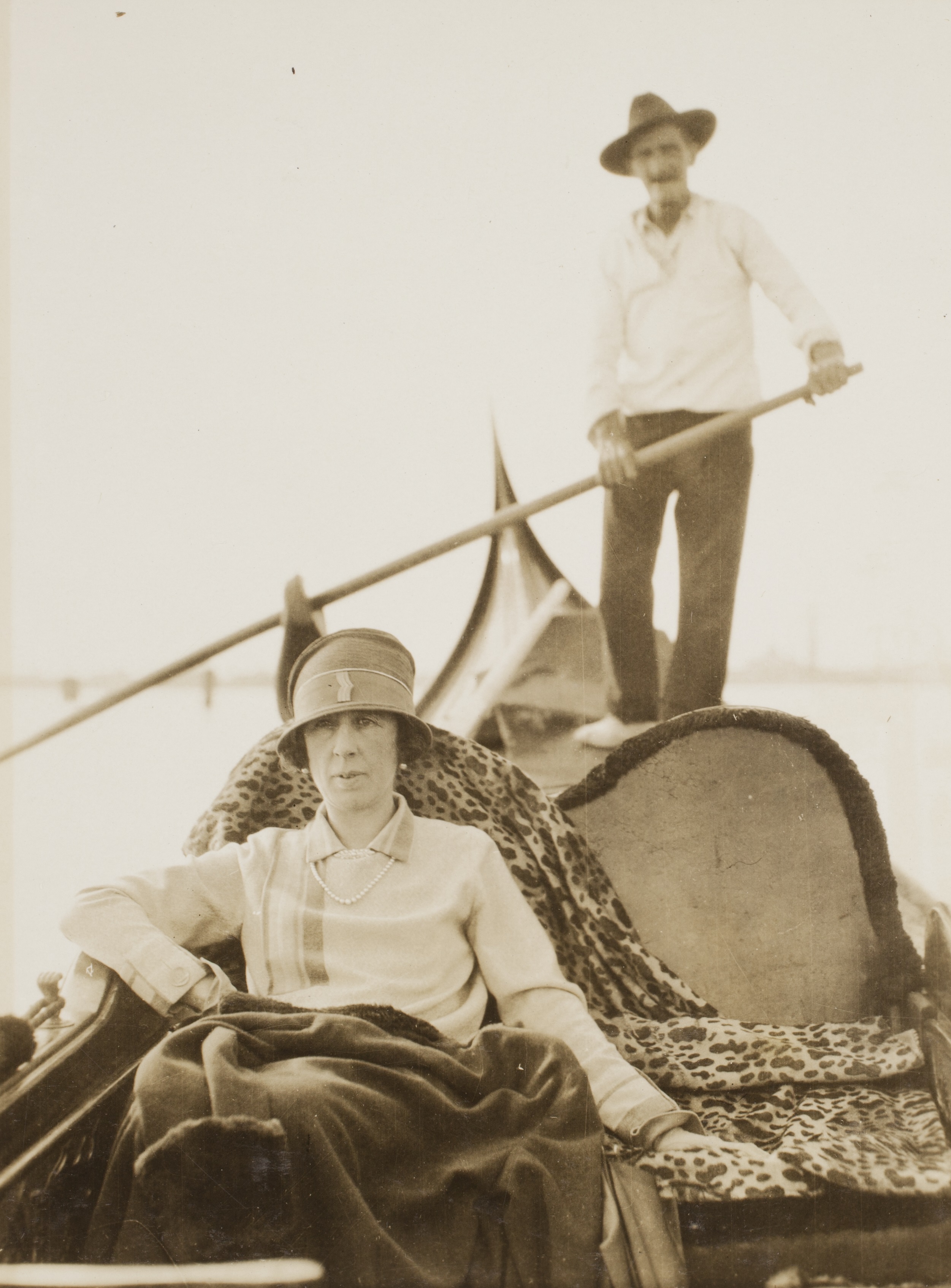 Woman sitting in gondala, man standing and holding rowing ore in gondola behind her