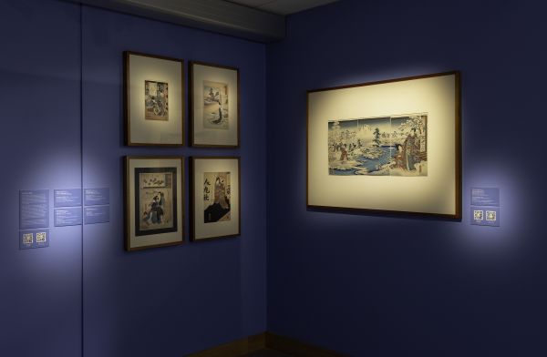Photograph of gallery space with framed works, painted walls lit by spotlights