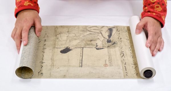Woman unrolling a scroll across a white tabletop