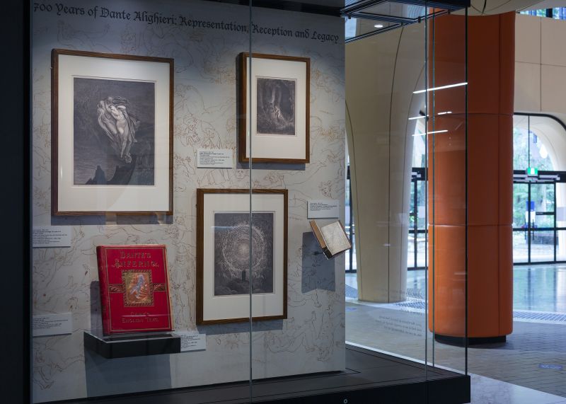 Glass display case, featuring rare books, on a printed background in a foyer space