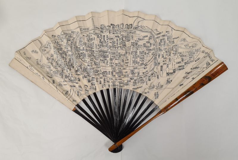 Wooden and paper fan with black map printed on cream paper.