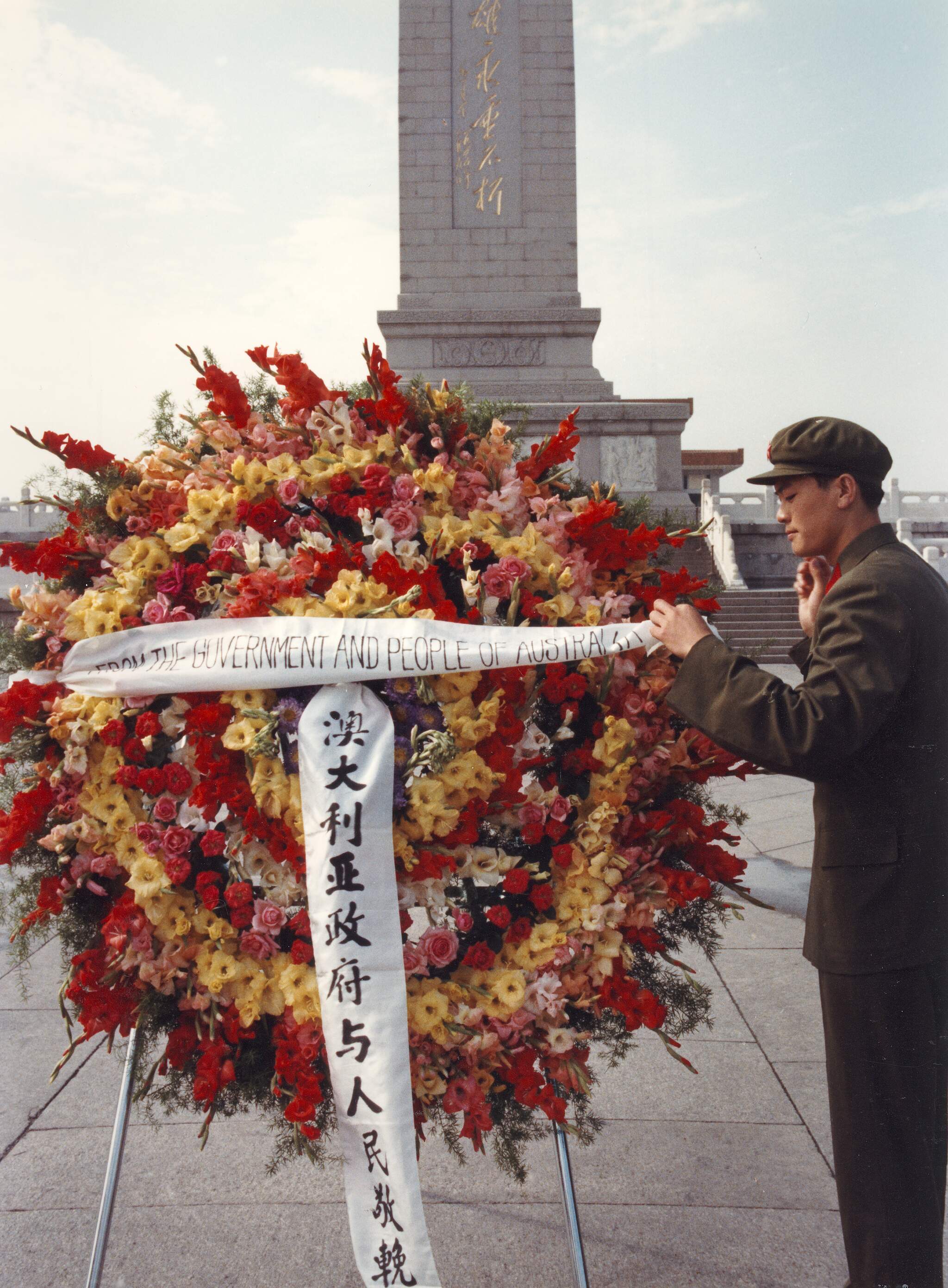 UMA-ITE-2005010300049. A Chinese soldier attaching a banner to an Australian wreath in front of the Monument to the People's Heroes in Tiananmen Square, Beijing, China, 1982. Photographer: Australian Information Service