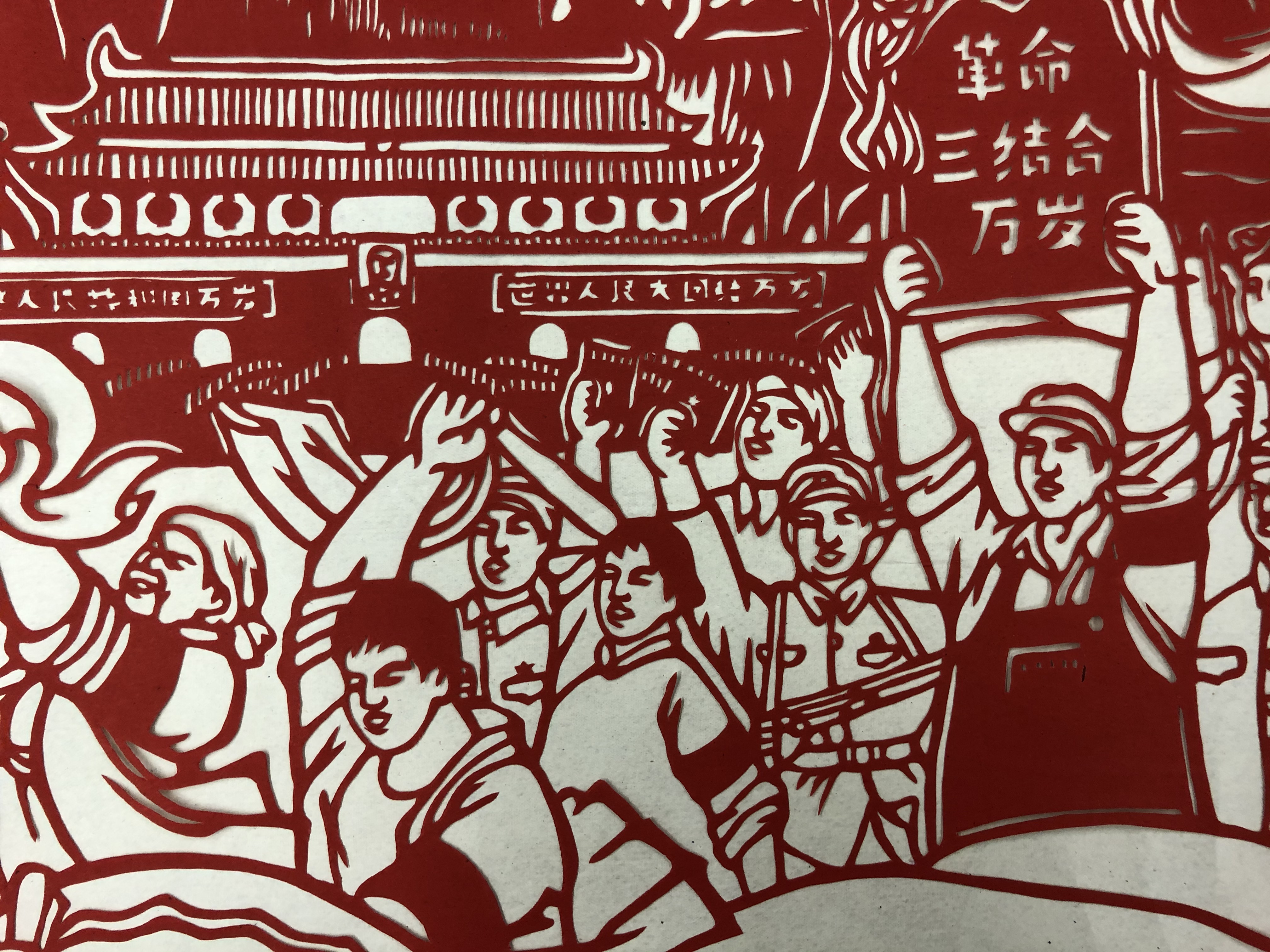 papercut post in red and white depicting a group of men and women marching in the street, some holding banners aloft