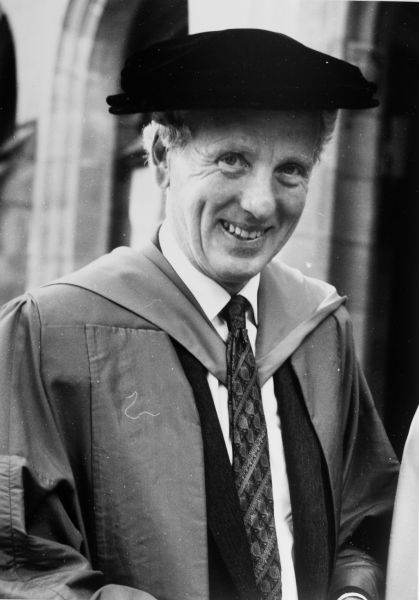 Black ans white photograph of Professor David Penington, head and shoulders, in academic attire looking at camera smiling