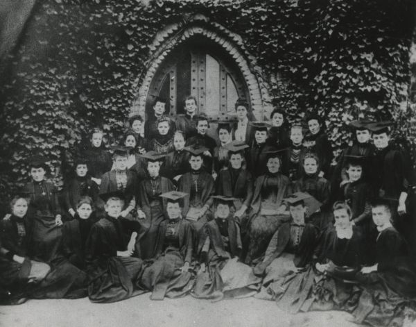 Group of women graduates, some dressed in mortar boards and ceremonial robes, 