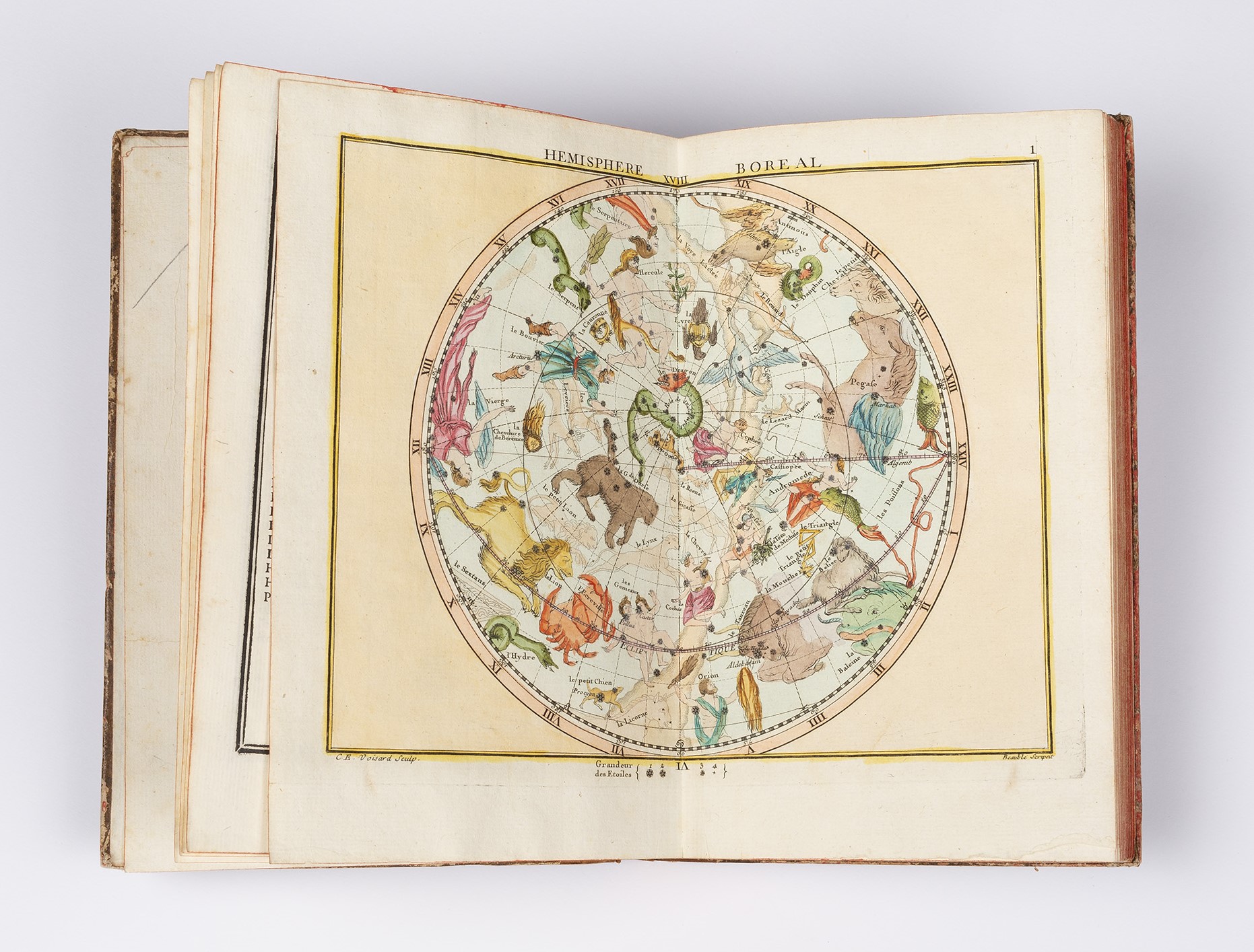 Aged book open to double page spread, with large illustrated and coloured map, on white tabletop